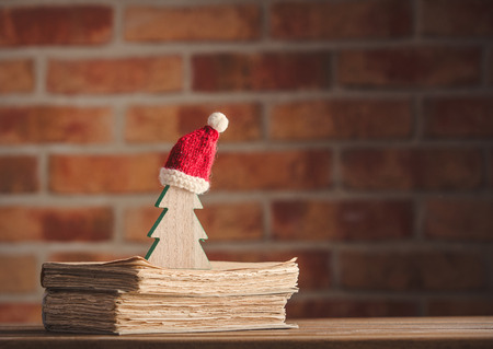 Santa Claus Christmas hat and tree with old books on wooden table at brick wall background. Libraryの写真素材