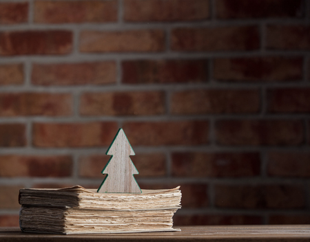 Christmas tree toy and old books on wooden table at brick wall background. Libraryの写真素材