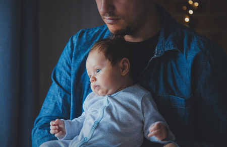 Photo of little infant in father's hands near a window. Image made with natural day light.の写真素材