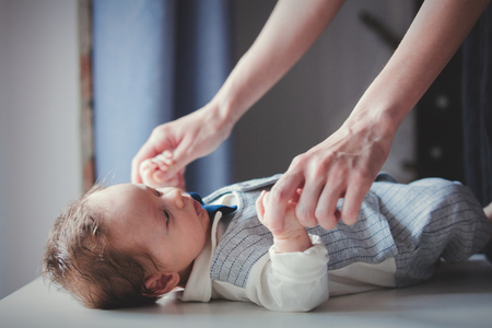 Photo of little infant and mother hands on white table near a window. Image made with natural day light.の写真素材