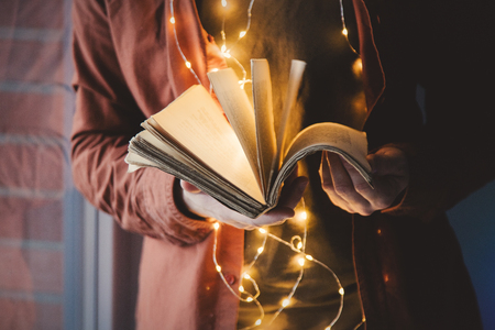 Adult young caucasian man holding book with lights.の写真素材