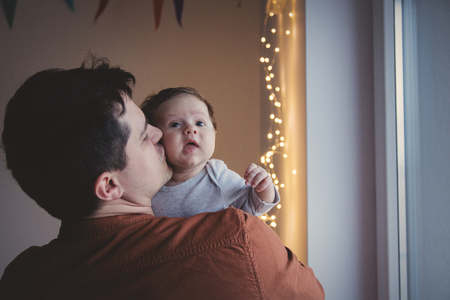 Young father holding little child on shoulder. Indoor image with focus on infant の写真素材