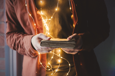 Adult young caucasian man holding book with lights.の写真素材