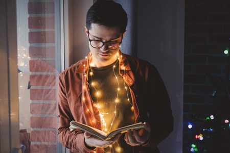 Adult young caucasian man reading book with lights.の写真素材