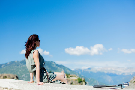 Woman sitting at precipice in Greece near camera. Trave image in summer timeの写真素材