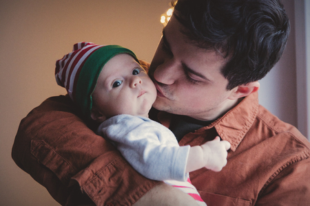Young father in eyeglasses play with little child on hands. Indoor image.の写真素材