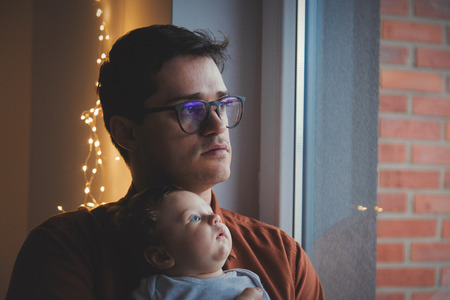 Young father in eyeglasses play with little child on hands indoor. の写真素材