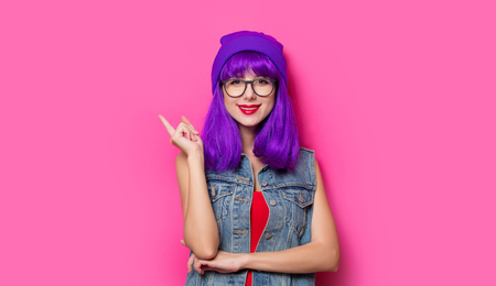 Portrait of young style hipster girl with purple hair on pink backgroundの写真素材