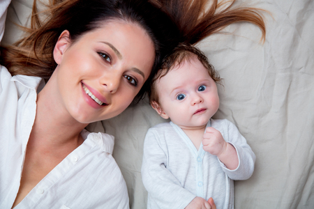 Mother and a little child lying down on bed backgroundの写真素材