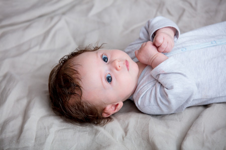 Portrait of little child lying down in bed.