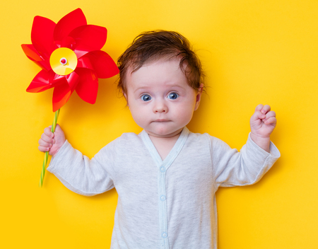 little baby with pinwheel toy on yellow backgroundの写真素材