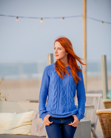 Young redhead girl in bue sweater resting in cafe on the beach in Hague, Netherlands の写真素材