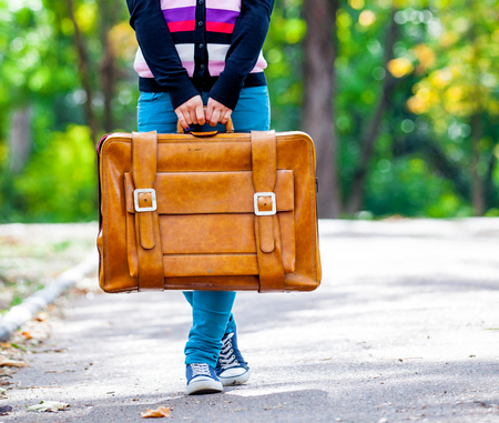 Young teen girt with suitcase in a park in sunny day の写真素材