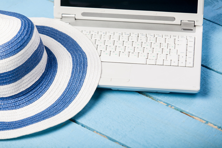 Hat and white computer on blue wooden table.の写真素材