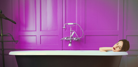 photo of beautiful young woman lying in bath and resting with her eyes closed の写真素材