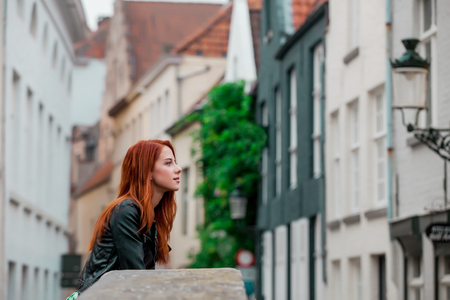 Young redhead girl rest on the street in Brugge, Belgium in autumn time season の写真素材