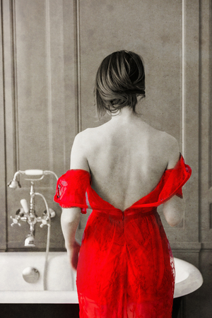 photo of beautiful young woman standing near bath and taking her dress off. Photo in old color image style.の写真素材
