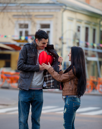 Young man giving a heart shape toy as a gift to young girl on the street. Odessa, Ukraine の写真素材