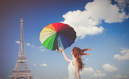 Young redhead girl with umbrella at Eiffel tower background の写真素材