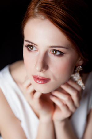 Portrait of young redhead woman with beautiful earrings on grey backgroundの写真素材