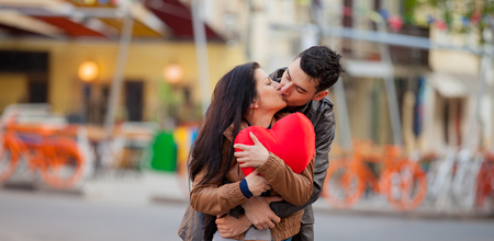 Young couple with heart shape toy kissing on the street in springtime.の写真素材