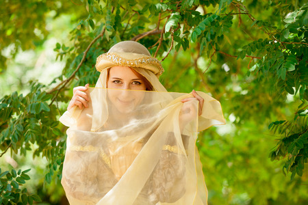 Young happy medieval girl near green branches of tree.の写真素材