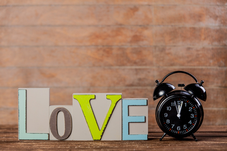 Retro alarm clock and text love on wooden backgroundの写真素材
