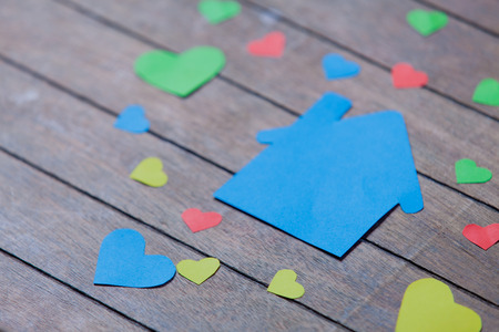 Paper house and heart shapes on wooden backgroundの写真素材