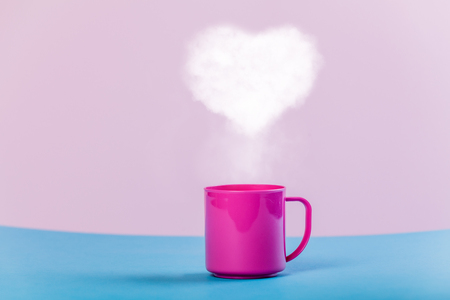 Cup of coffee with ehart shape steam on a tableの写真素材