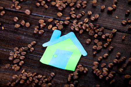 Paper house and coffee beans on wooden backgroundの写真素材