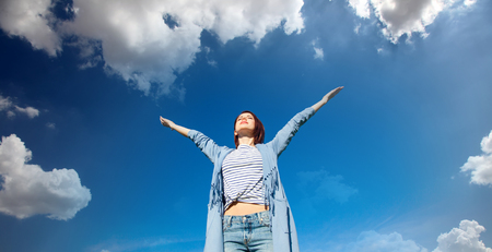 Young style redhead girl in modern clothes on blue sky with clouds backgroundの写真素材