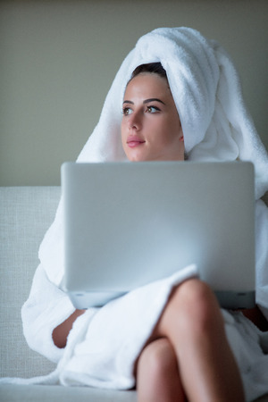 young businesswoman in bathrobe with notebook working in a hotelの写真素材