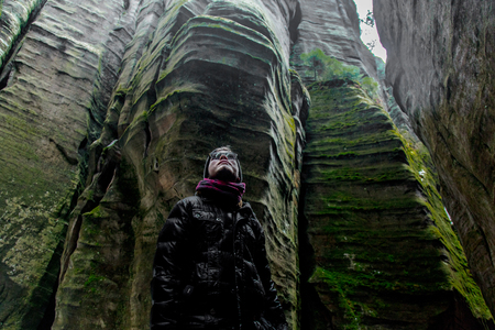 Young hipster boy in sunglasses looking up in rocks forestの写真素材