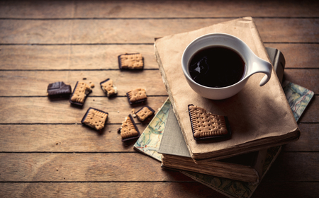 White cup with coffee and books, cookie on wooden table. High angle viewの写真素材