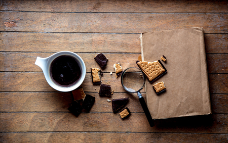 White cup with coffee and books, cookie on wooden table. High angle viewの写真素材