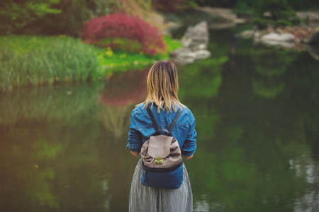 Young stylish girl have a rest in springtime japanese garden near a pondの写真素材