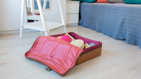 Vintage suitcase liyng down on floor with clothes inside before a summer travelの写真素材