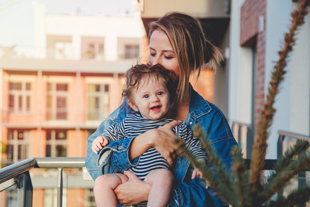 Young mother with a child standing on balcony in summer day.の写真素材