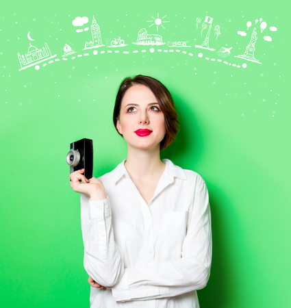 portrait of beautiful smiling young woman with retro camera on the wonderful studio green background