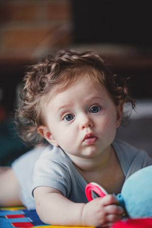 little curly baby boy sitting at floor in loft flat.の写真素材