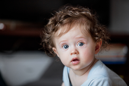little curly baby boy sitting at floor in loft flat.の写真素材