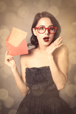 portrait of beautiful young woman holding envelope and letter in it on the wonderful grey studio backgroundの写真素材