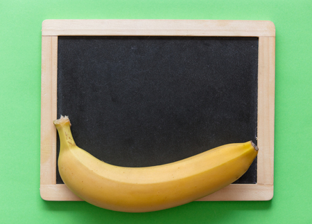 Yellow banana with blackboard on green background. Natural lightの写真素材