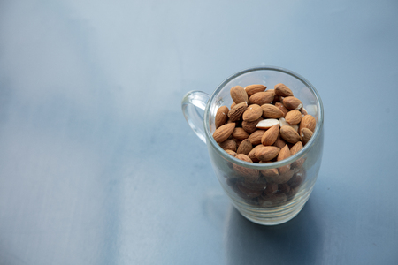 Glass cup and almonds on metal grey background. Above viewの写真素材