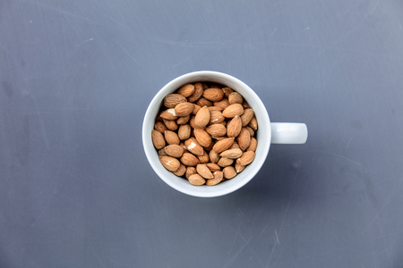 White cup full of almonds on grey background. Above viewの写真素材