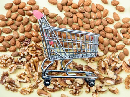 Almonds and walnuts with supermarket cart on green background. Above viewの写真素材