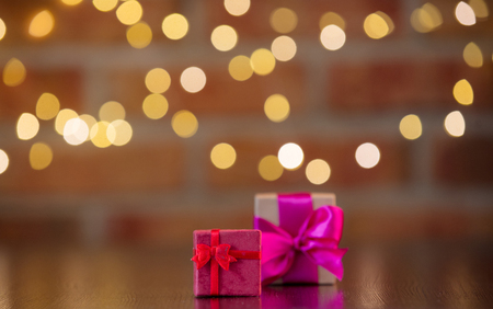 two handmade gift boxes on wooden table with fairy lights on bokeh backgroundの写真素材