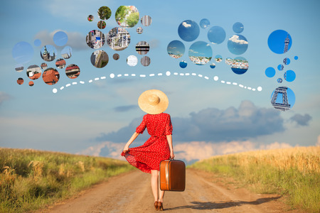 Redhead girl with suitcase at outdoor dreaming about travel around the worldの写真素材