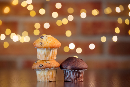 Homemade classic and chocolate cupcakes with fairy lights in bokeh.の写真素材