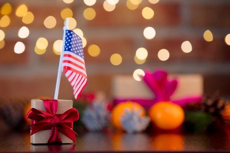 gift box and flag of the USA on background with fairy lights in bokeh. Christmas Holiday seasonの写真素材